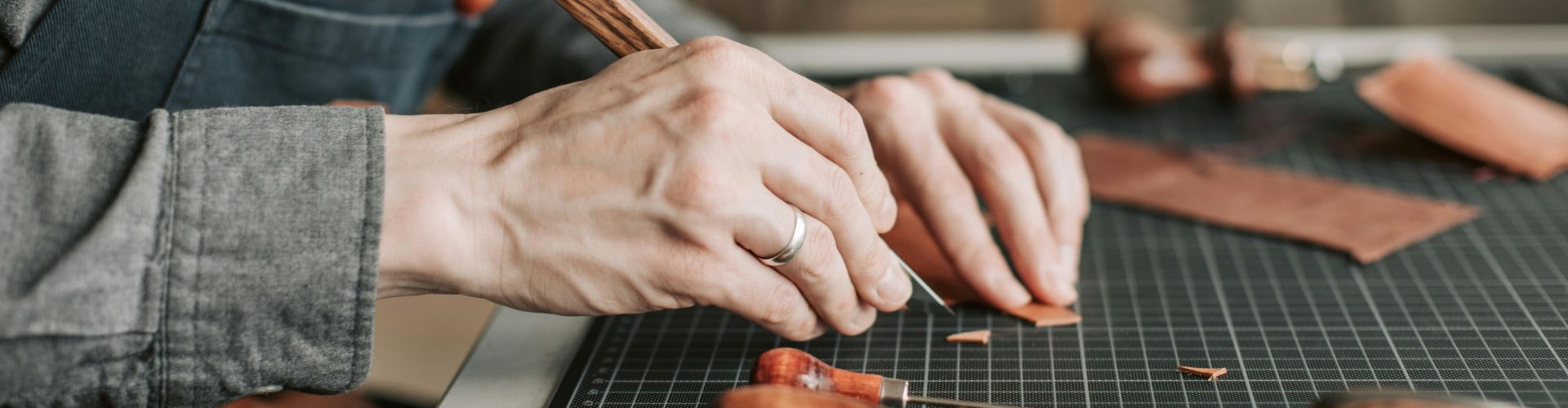 Saddlers' Company news: SEG Level 1, hands cutting leather with a knife on a cutting mat