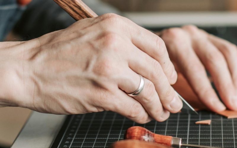 Saddlers' Company news: SEG Level 1, hands cutting leather with a knife on a cutting mat