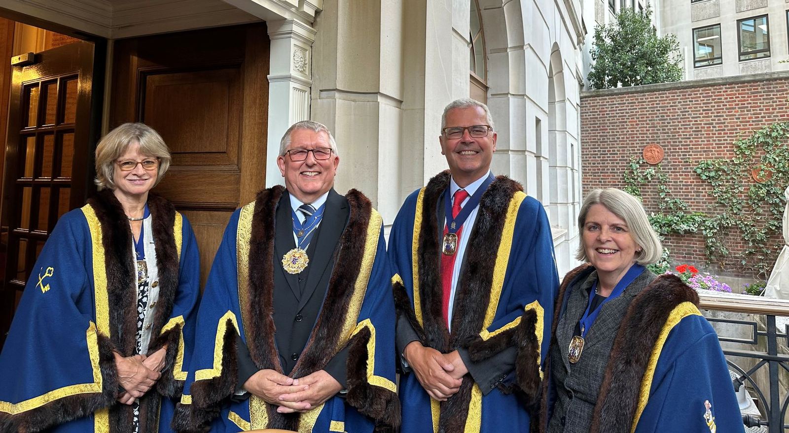 Mark Romain MBE, Prime Warden, second from left, with the Wardens for 2026/27 in their robes outside Saddlers' Hall